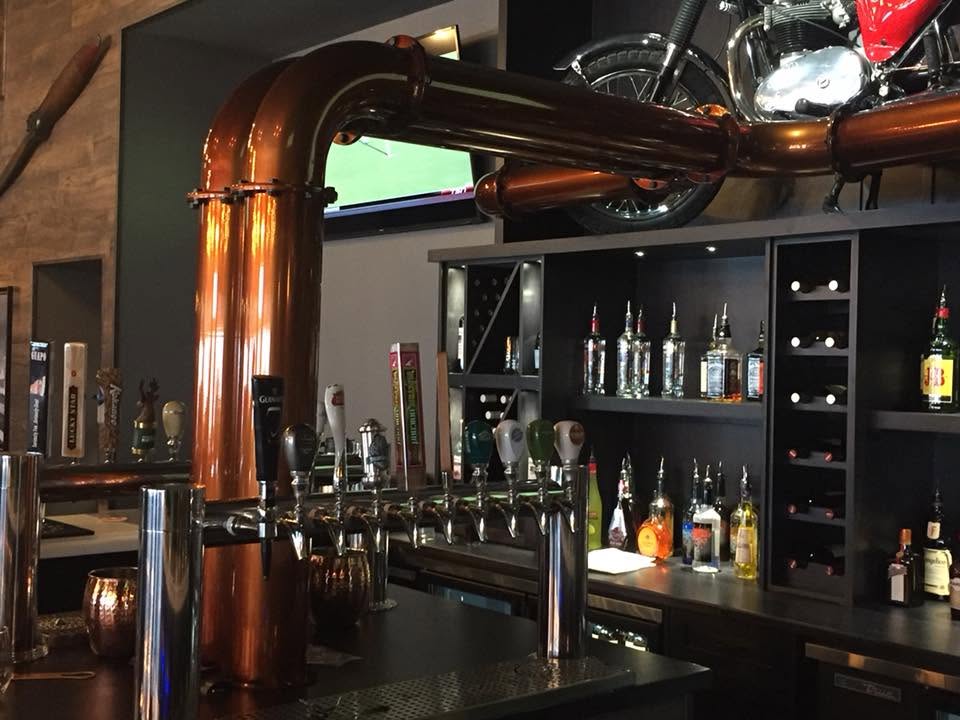 Custom curved copper tap tower installed on hardwood bar
