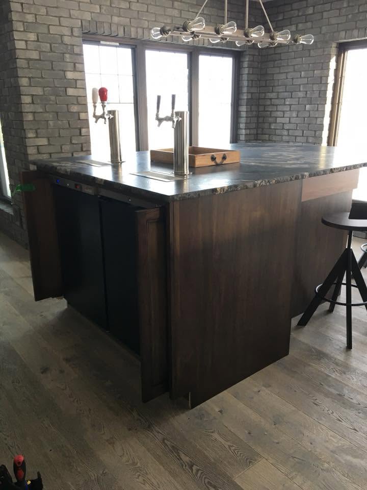 Dual tap kegerator built into a kitchen island with soapstone counter